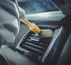 paint brush being used to clean air vent dust in automotive vehicle